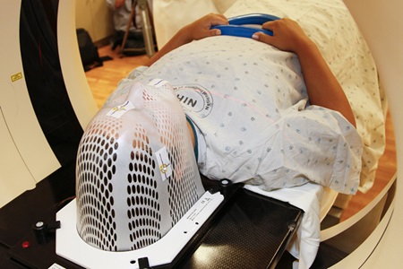 A patient model wearing a short face mask is positioned in a computed tomography (CT) scanner to obtain images of a tumor before radiation therapy